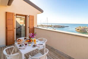 Ein Balkon mit Frühstückstisch mit Blick auf eine Marina und Boote.