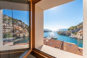Eine Küstenstadt mit Gebäuden am Wasser, einem klaren Himmel und Blick durch ein Fenster.