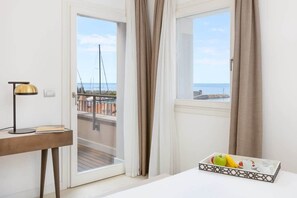 A room with a view of the sea, a desk with a lamp, and a tray with fruits and cups. - La tempesta perfetta - Portopiccolo Apartments (Duino-Aurisina)