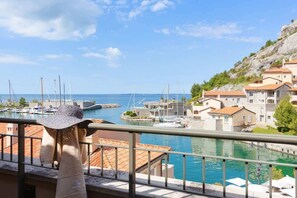 A coastal town with a marina, stone buildings with red-tiled roofs, and a clear blue sky. - La tempesta perfetta - Portopiccolo Apartments (Duino-Aurisina)