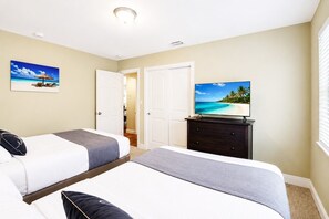Una habitación de hotel con dos camas, un televisor en una cómoda y una puerta que da a un baño.