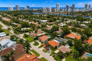 Vista aérea de una zona residencial con casas, palmeras y un puerto deportivo.
