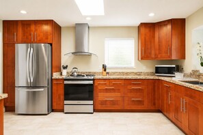 A modern kitchen with stainless steel appliances, wooden cabinets, and a granite countertop.
