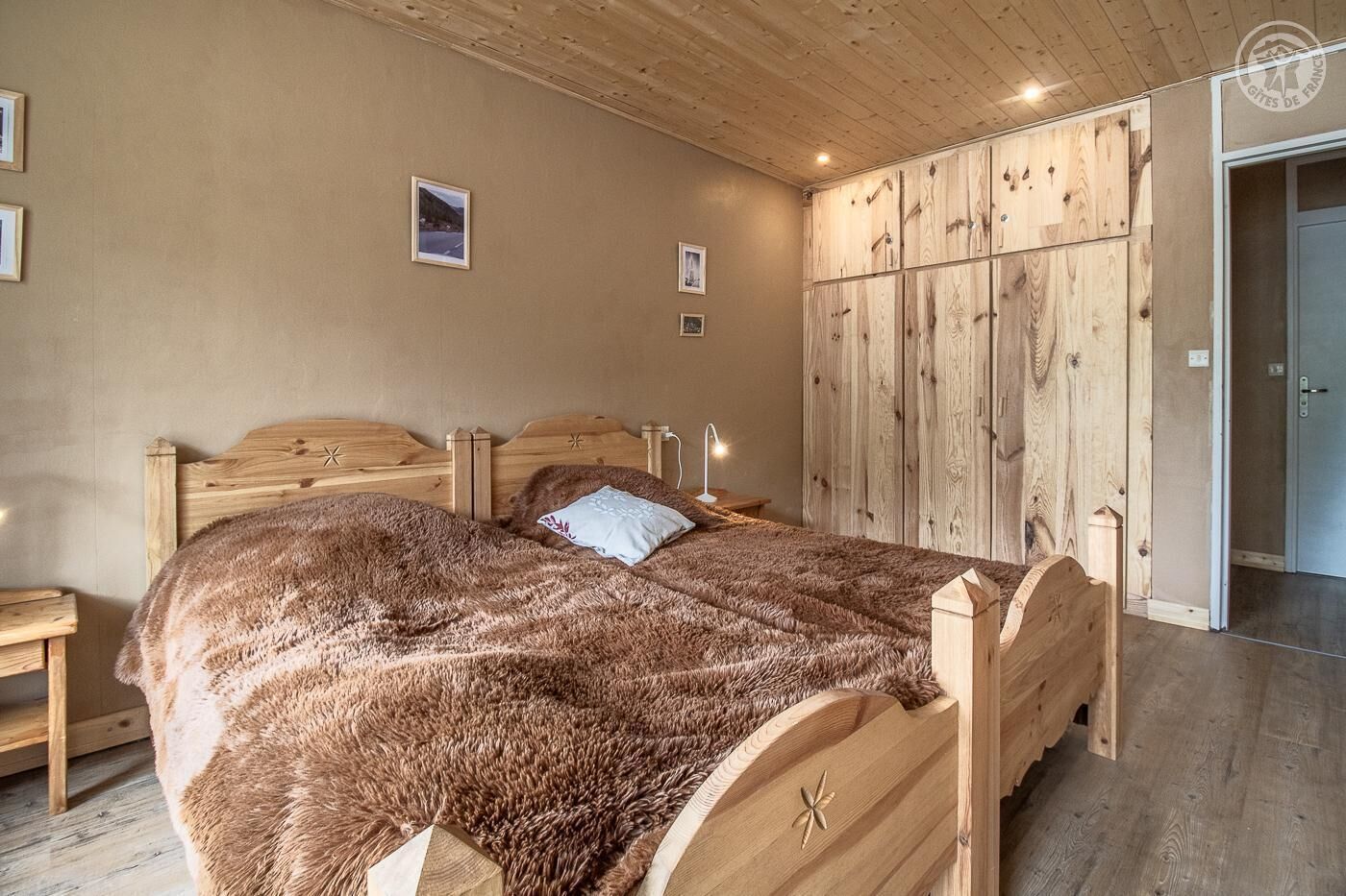 Une chambre avec un lit en bois, une grande armoire et un plancher en bois.