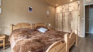 A bedroom with a wooden bed, a large wardrobe, and a wooden floor. - L'iseran - VAL D'isere (VAL D'ISERE)