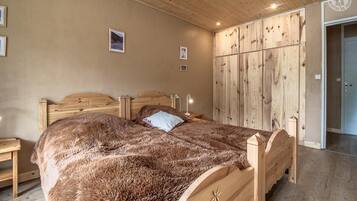 Une chambre avec un lit en bois, une grande armoire et un plancher en bois.