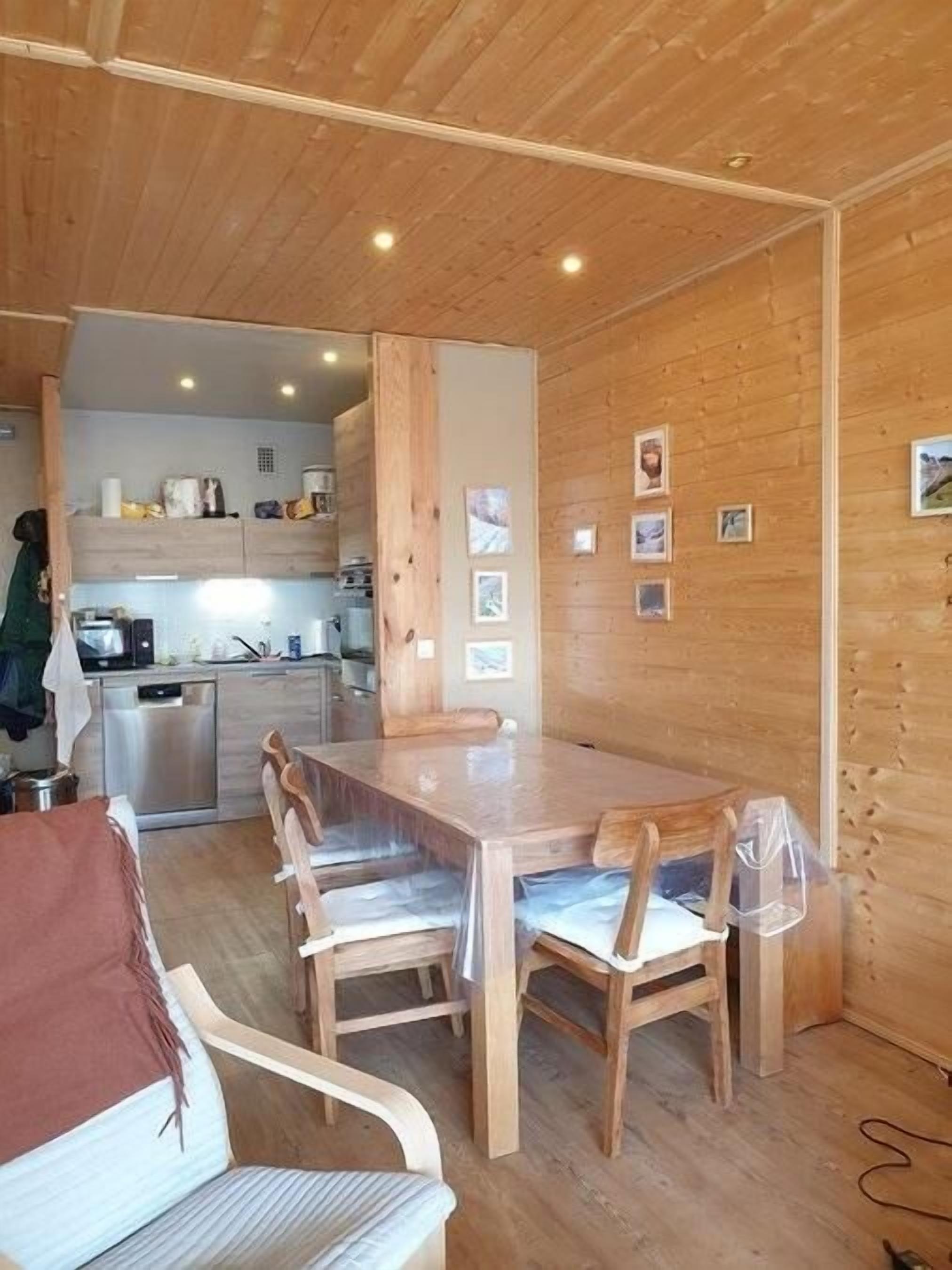 Un intérieur en bois comprenant une table à manger, des chaises et un coin cuisine.