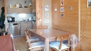 A wooden interior with a dining table, chairs, and a kitchen area. - L'iseran - VAL D'isere (VAL D'ISERE)