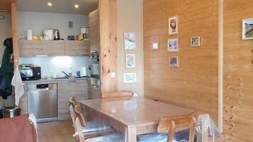 Un intérieur en bois comprenant une table à manger, des chaises et un coin cuisine.