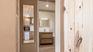 A hallway with wooden flooring, a wooden wardrobe, and a view into a kitchen area with a refrigerator and a sink. - L'iseran - VAL D'isere (VAL D'ISERE)