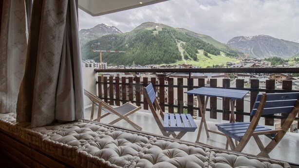 A balcony with a view of mountains, a wooden fence, and a cushioned bench. - L'iseran - VAL D'isere (VAL D'ISERE)