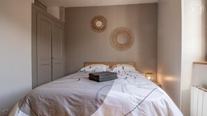 A bedroom with a bed, two wall decorations, a bedside lamp, and a radiator. - LA P'tite Pierrue - Arvillard (ARVILLARD)