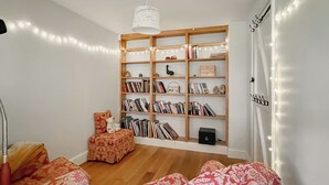 Una habitación acogedora con una estantería de madera, un sillón cómodo y un sofá estampado.