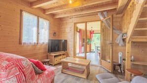 En mysig stuga i trä med TV, soffa och matbord.