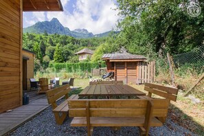 A wooden cabin with a deck, outdoor seating, and a mountain view. - Chez Cathy - Saint Remy DE Maurienne (SAINT REMY DE MAURIENNE)