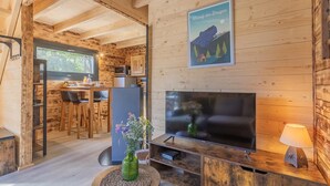 Un intérieur en bois comprenant un téléviseur, un coin repas et une cuisine.