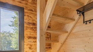 Un intérieur en bois avec un escalier, une fenêtre et une plante.