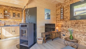 Un intérieur de chalet chaleureux avec des murs en bois, un four encastré, un téléviseur à écran plat et une cheminée.