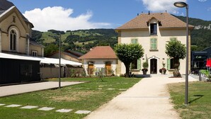 A rural village with a central building featuring a tiled roof and a small balcony. - LA Cure Gourmande - LA Sure (SAINT CHRISTOPHE LA GROTTE)