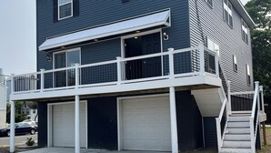 Una casa a due piani con un balcone, un garage e una scala che conduce al piano superiore.