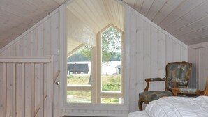 A bedroom with a sloped ceiling, a large window, a wooden door, and a chair. - 2 bedroom cozy home in årjäng (Årjäng)