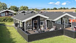 Un edificio moderno con varias habitaciones, ventanas amplias y un espacio exterior con césped.
