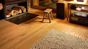 Un salon chaleureux avec une cheminée, un petit tabouret, une table avec une lampe et un haut-parleur.