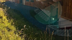 Une cabane en bois avec un toit en pente, une entrée en verre et une vue sur les montagnes en arrière-plan.