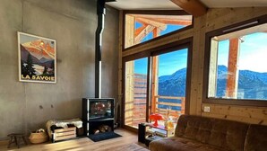 Un salon chaleureux avec une cheminée, de grandes fenêtres et une vue sur les montagnes.