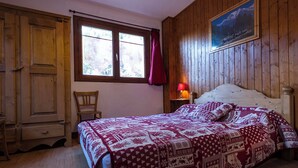 Un dormitorio con una cama de madera, una ventana con cortinas, una silla y un cuadro en la pared.