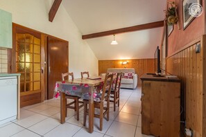 A dining area with a wooden table and chairs, a sofa, and a kitchen area with a refrigerator. - Chalet Faviere - VAL Cenis (VAL CENIS)