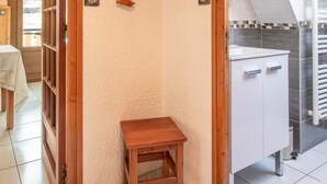 Eine Raumecke mit einer hölzernen Bank, einem Schrank und einem Wandkunstwerk mit dem Schriftzug 'Bienvenidos'.