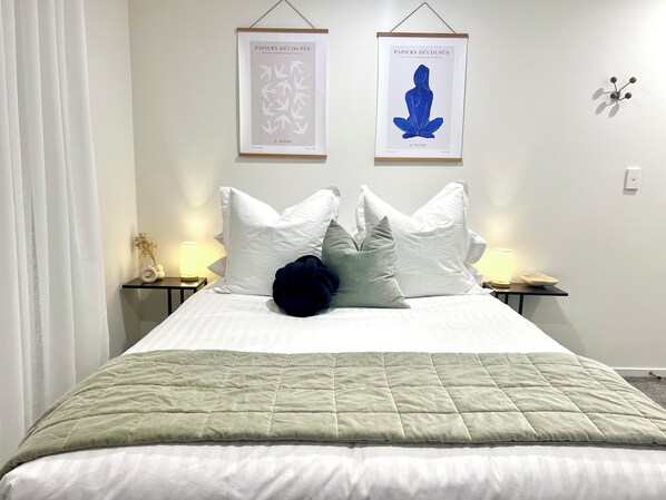Relax in a serene bedroom with a large bed, framed artworks, and a minimalist aesthetic.