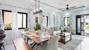 A modern dining area with a wooden table set for four, surrounded by grey upholstered chairs. - Beautiful Modern Vacation Home (Ocho Rios)