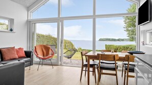 Un salon moderne doté d’une grande porte-fenêtre coulissante donnant sur un balcon avec vue sur un lac.
