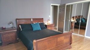 A bedroom with a wooden bed, a nightstand, a dresser, and a mirror.