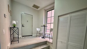 A staircase leading to a room with a window, a door, and a small table with a plant. - NEW Cozy Apt Bright + Modern W/D (Albany)