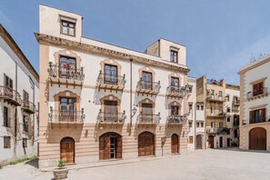 A historic building with multiple balconies, arched doorways, and a courtyard.