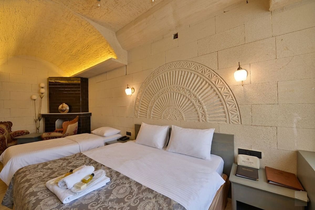 Ein Hotelzimmer mit zwei Betten, einem Kamin, einer Wanddekoration und einem Nachttisch mit Lampe.
