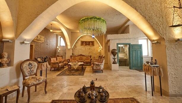 A spacious interior with high arched ceilings, a central seating area with sofas and chairs, a chandelier, and a dining table with tea sets. - Ashab-ı Kehf Cappadocia House (Nevsehir)