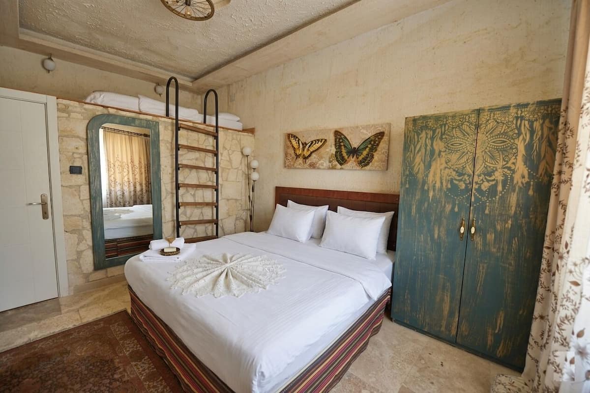 Ein Schlafzimmer mit Bett, Spiegel, Kleiderschrank und Schmetterlingsbildern an der Wand.