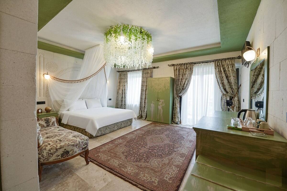 Ein Schlafzimmer mit Bett, Stuhl, Nachttisch, Spiegel und grüner Wand.