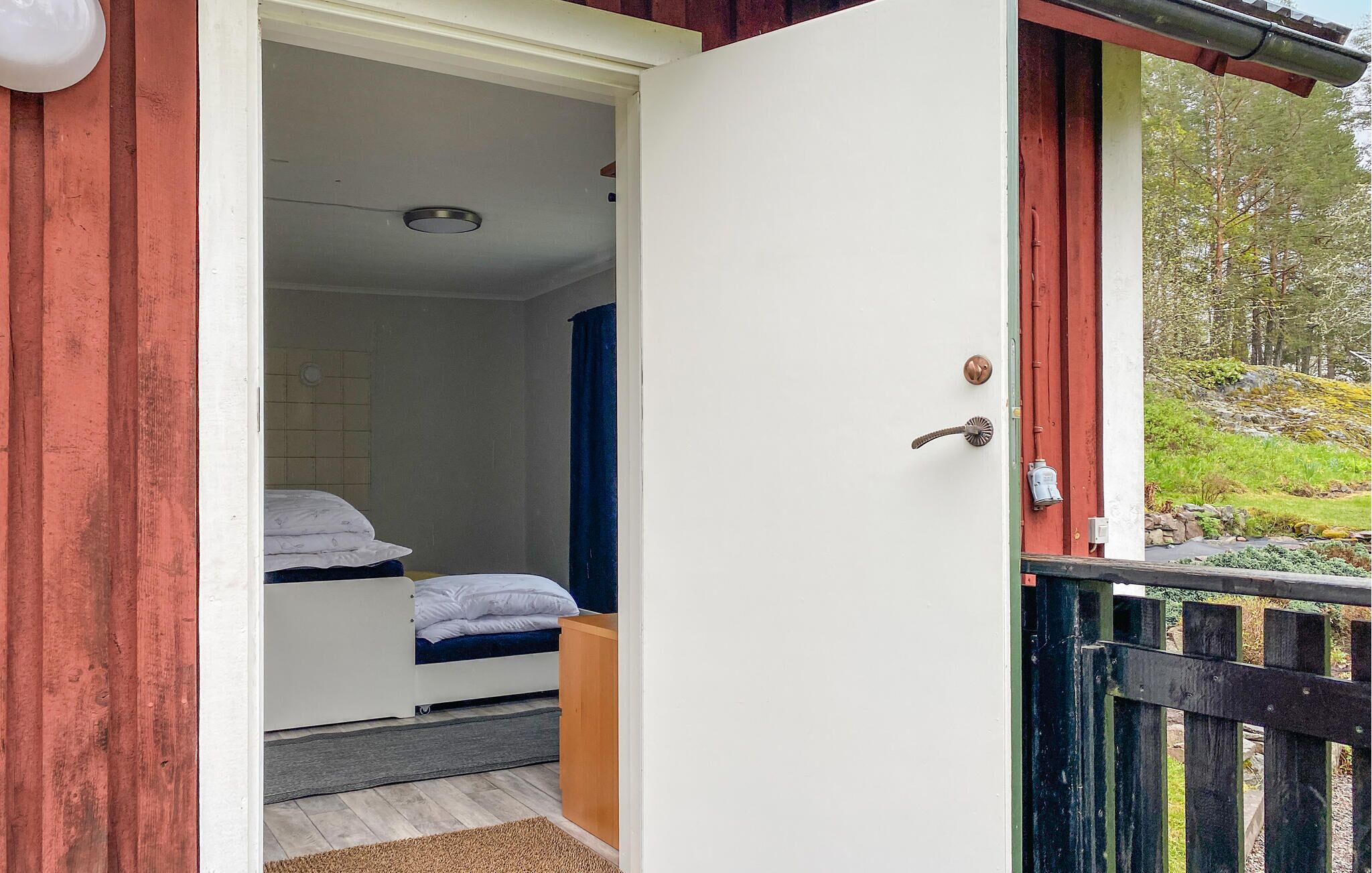 A single bedroom with a bed, a window, and a door leading to an outdoor area.