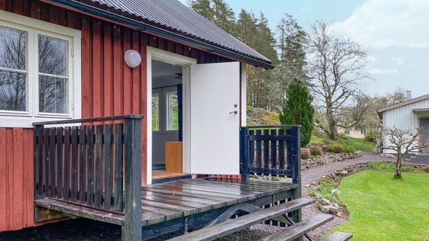 Une maison en bois avec un porche, une porte et un petit jardin.