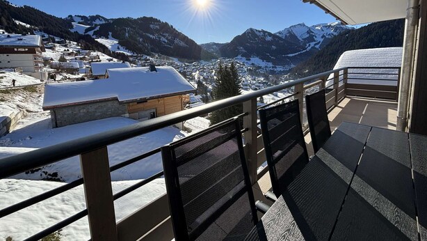 Un balcón con vistas a un pueblo cubierto de nieve y montañas.