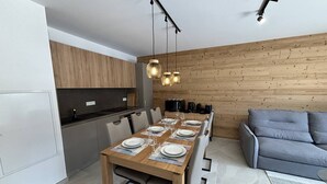 Una cocina moderna con armarios de madera, una mesa de comedor para seis personas y un sofá gris en la zona de estar.