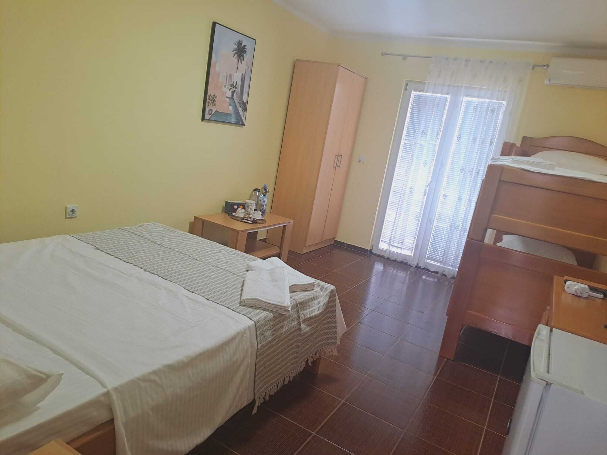 A hotel room with a bed, a desk, a wardrobe, and a window with blinds.