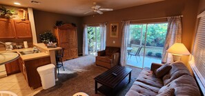 A living room with a sofa, coffee table, and a dining area with a cabinet and sink.