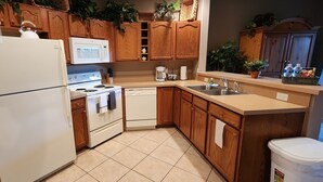 Una cocina con armarios de madera, un refrigerador blanco, un microondas, una estufa, un lavavajillas y un lavabo.