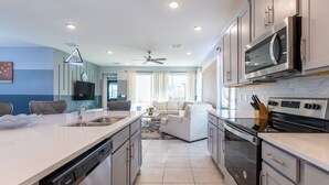 A modern kitchen with a central island, built-in appliances, and a dining area with a sofa.